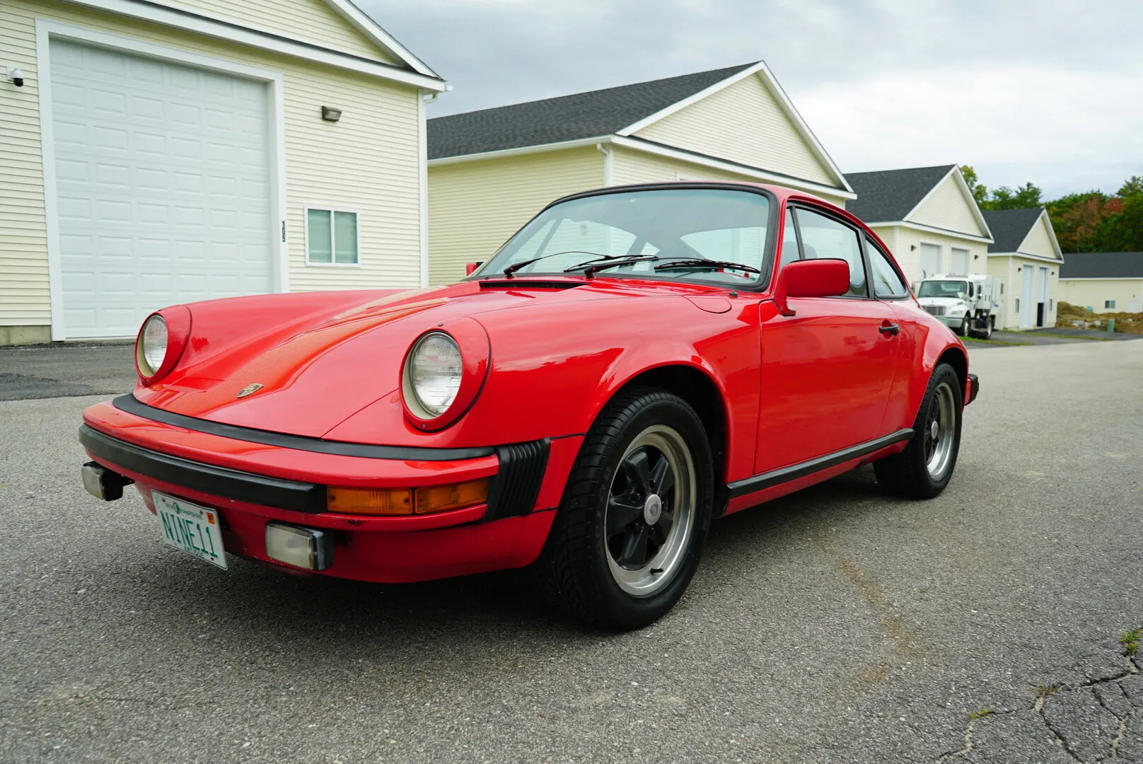 Red Porsche 911 SC, front three-quarter view in a driveway